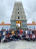 A group photo of happy travelers with their local guide in front of a historic temple.