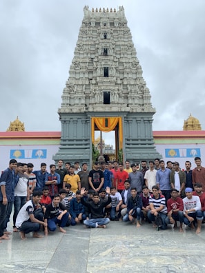 A group of travelers smiling and posing in front of a famous Indian monument