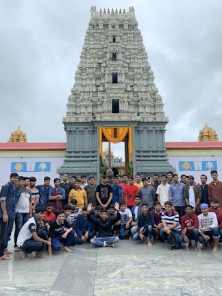 A group of happy travelers posing in front of a historic temple in Tamil Nadu.