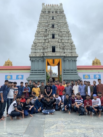 Family group smiling happily in front of the ancient Somnath temple under clear blue skies.