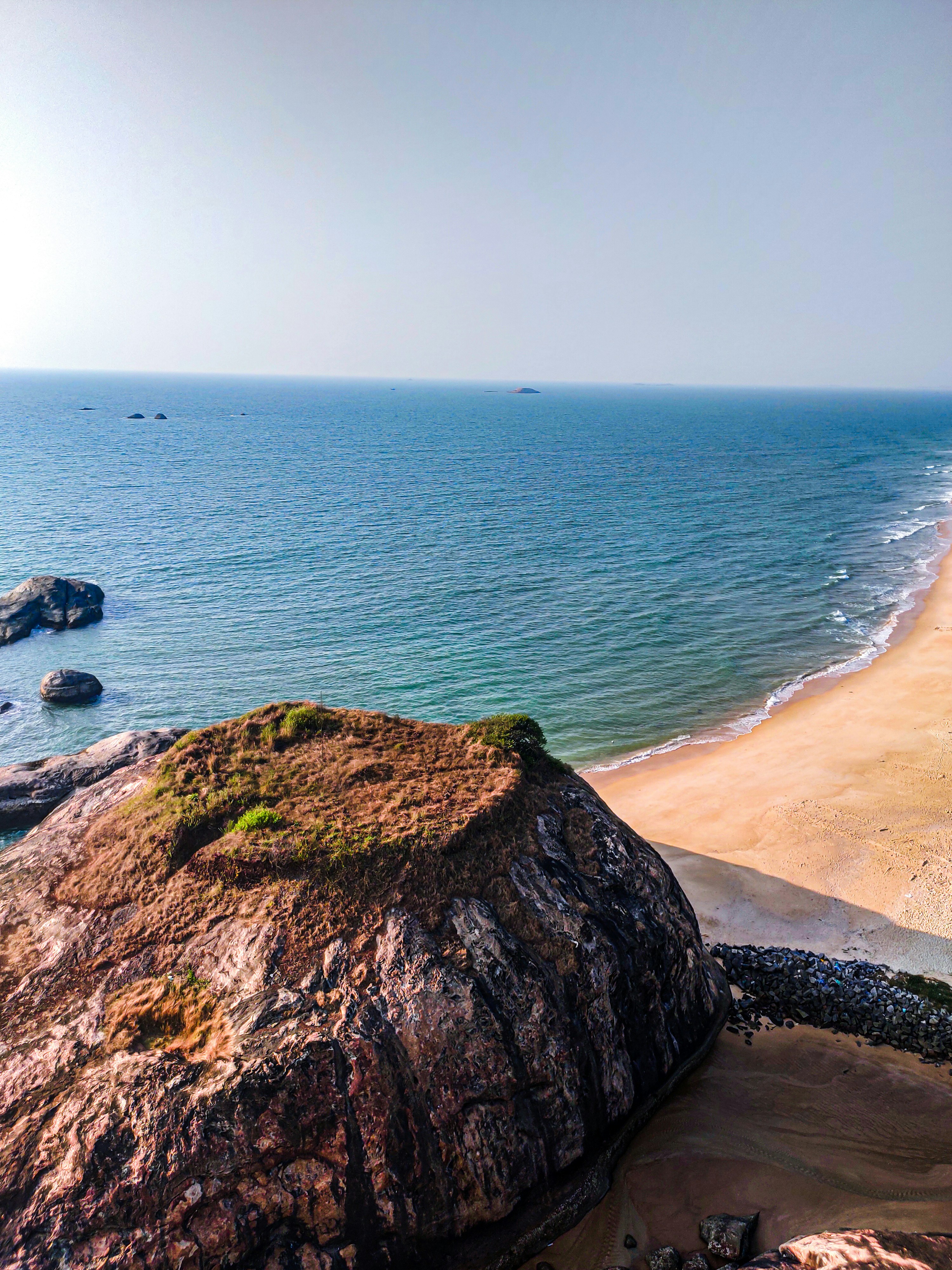 brown sand beach with green grass and blue sea during daytime