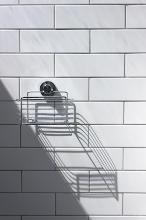 black and silver round analog watch on white ceramic wall tiles