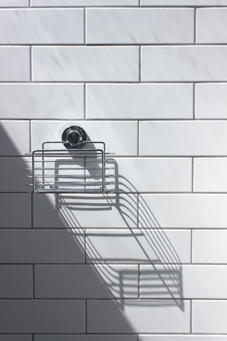 black and silver round analog watch on white ceramic wall tiles