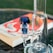 A close-up of a glass bong with a blue accented mouthpiece, placed on a table. In the background, a blurred book with a vibrant red and white cover is visible.
