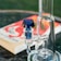 A close-up of a glass bong with a blue accented mouthpiece, placed on a table. In the background, a blurred book with a vibrant red and white cover is visible.