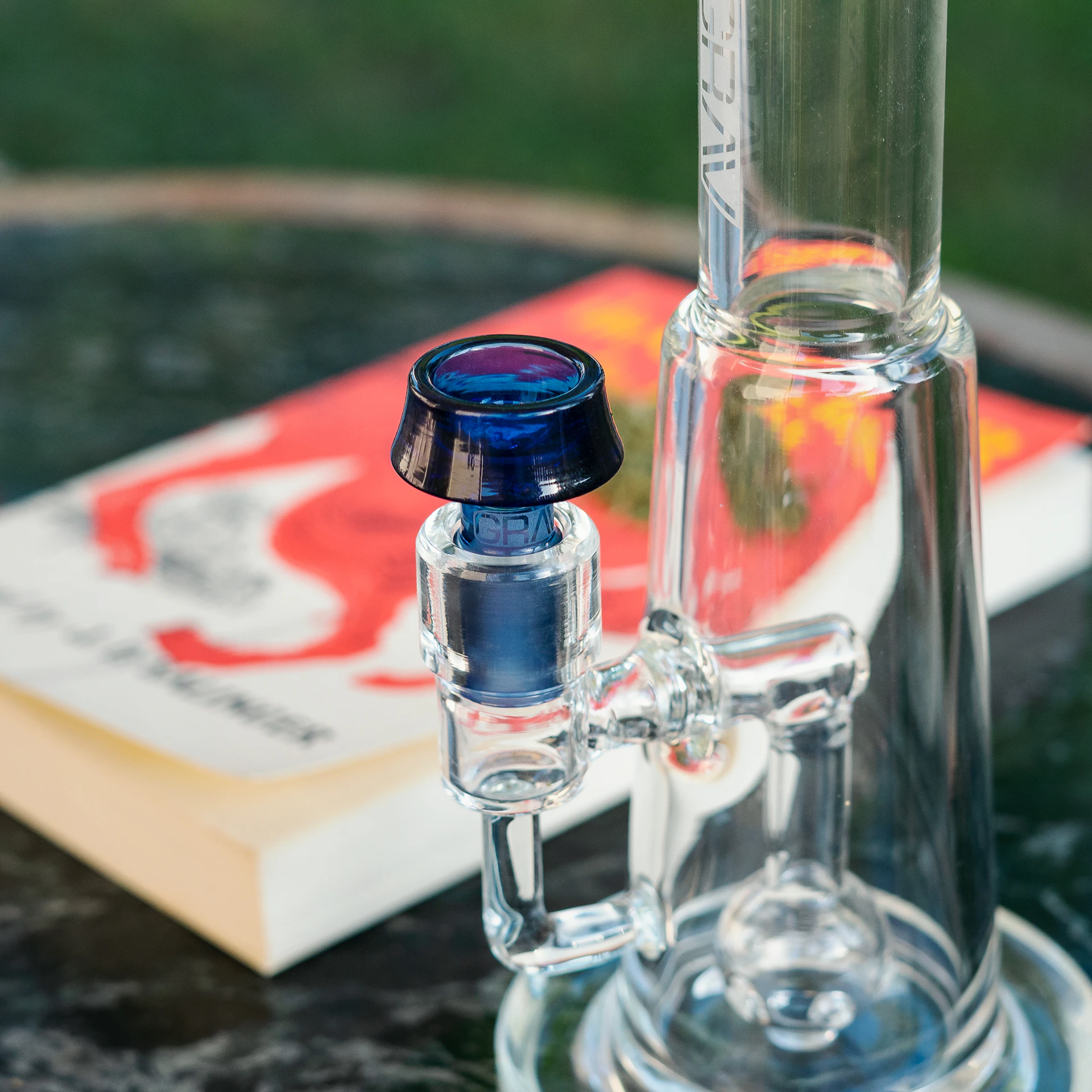 A close-up shot of a sleek glass bong with water droplets, set against a dark backdrop that accentuates its smooth curves and clarity.