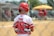 A happy young baseball player holding a Hicksville Baseball bat on a sunny afternoon at the local field.
