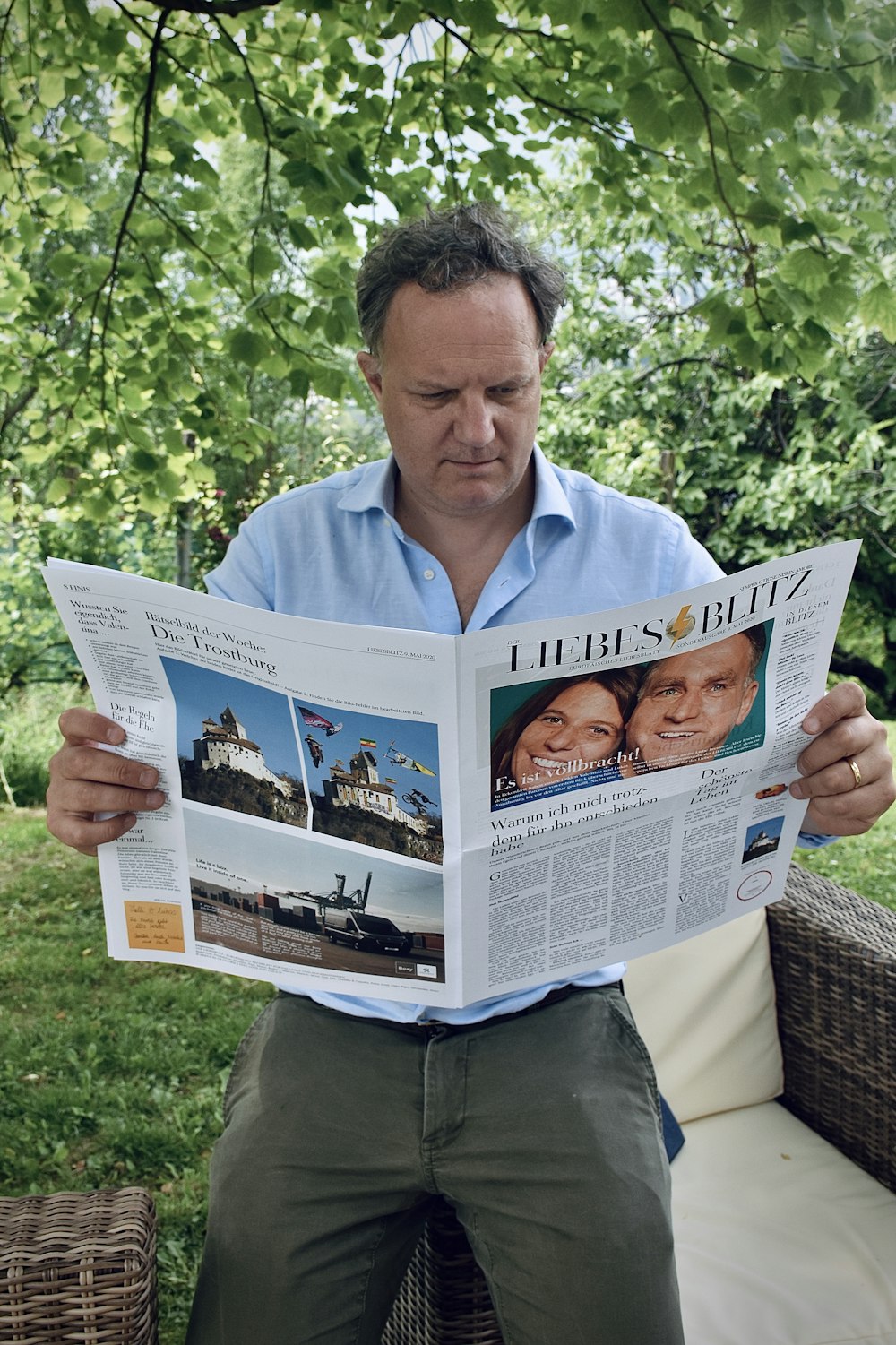 man in blue dress shirt holding newspaper