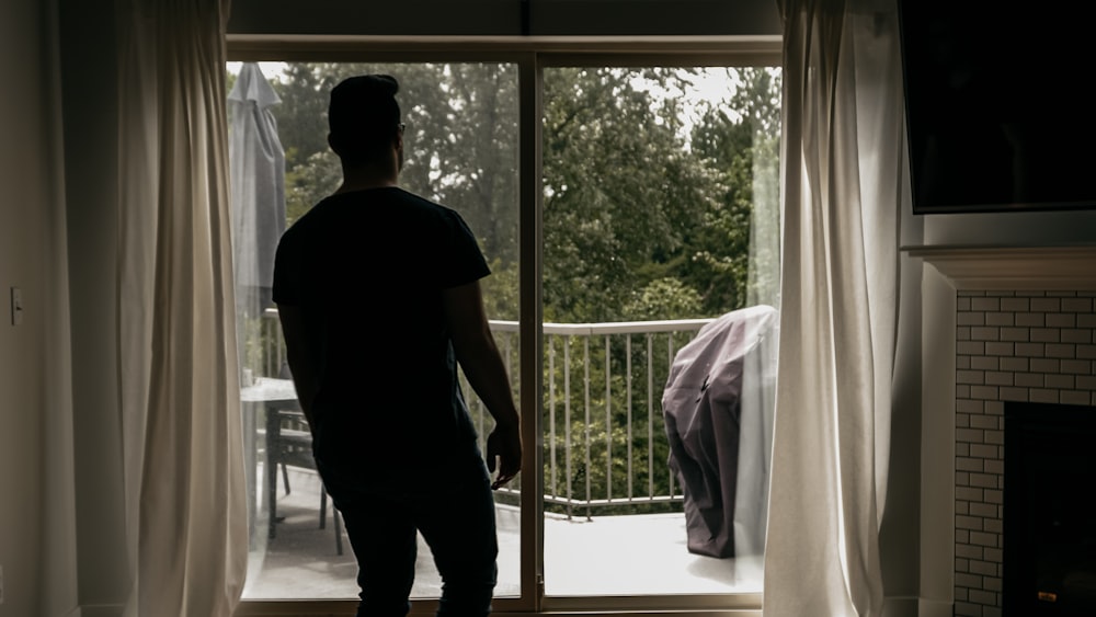 man in black t-shirt standing near window