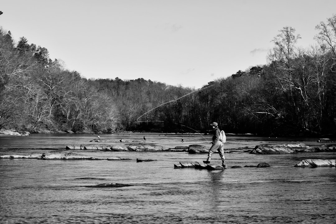 grayscale photo of man riding on boat on river