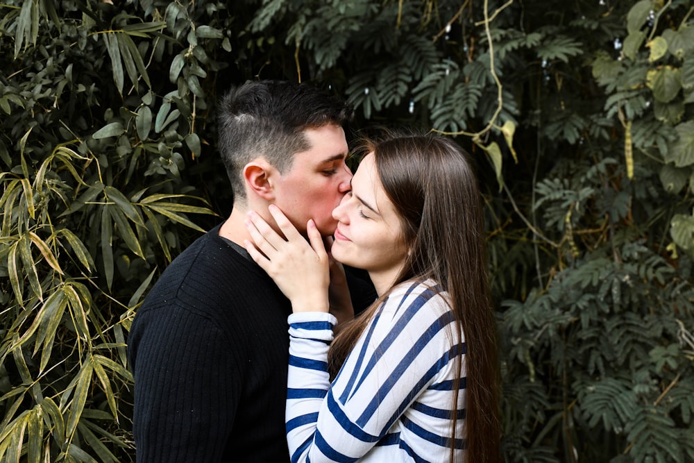 man in black suit kissing woman in white and blue striped long sleeve shirt