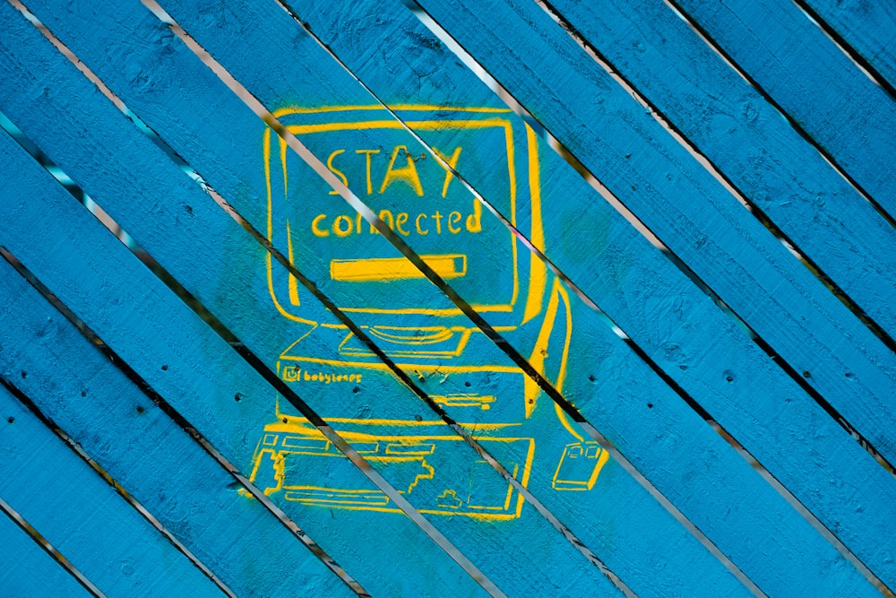 a picture of a blue and yellow sign on a wooden surface