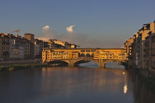 brown concrete building near river during daytime in Ponte Vecchio Italy