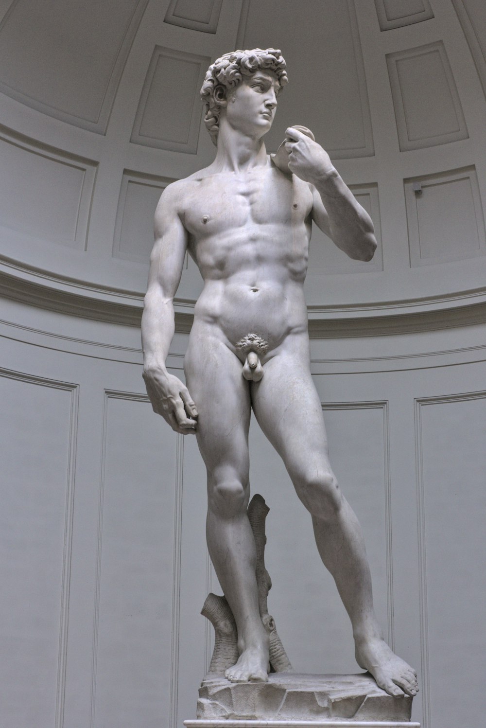 estátua do homem nu perto da parede de madeira branca