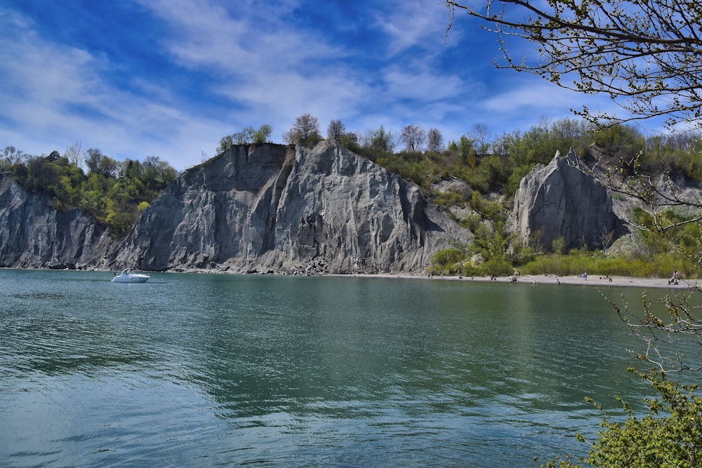 green and gray rocky mountain beside body of water during daytime