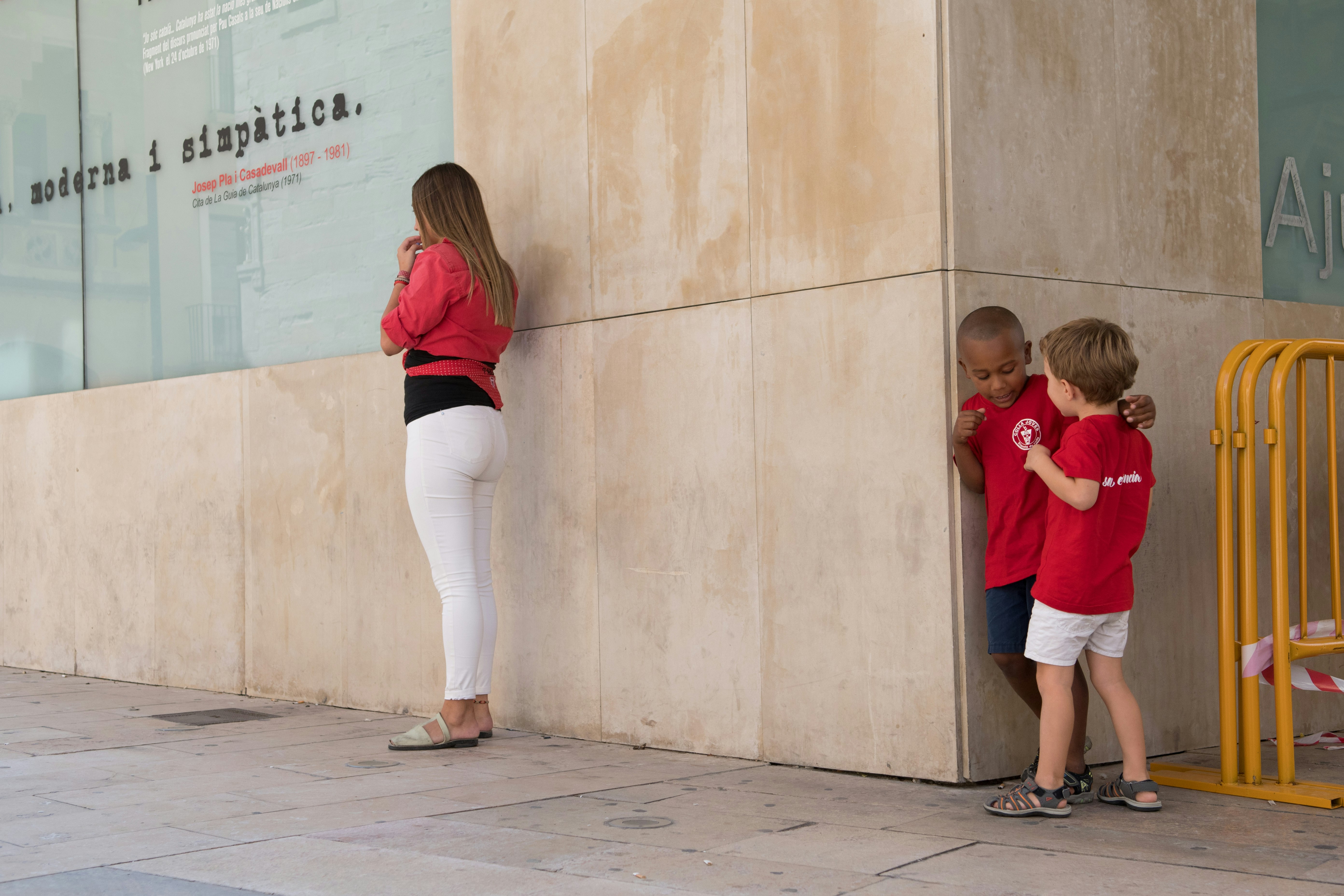 woman in red shirt and white pants standing beside boy in red shirt