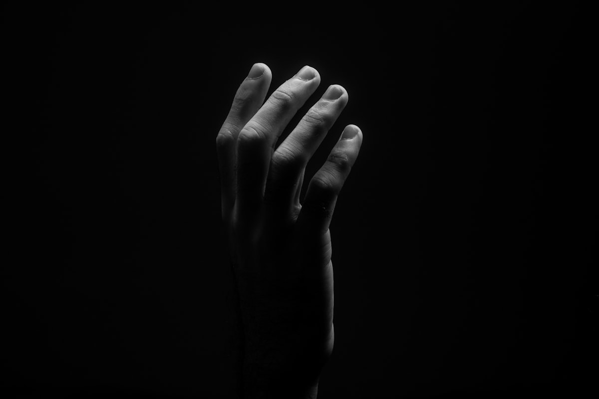 Black and white photo of a light colored hand dramatically lit in three quarter view.