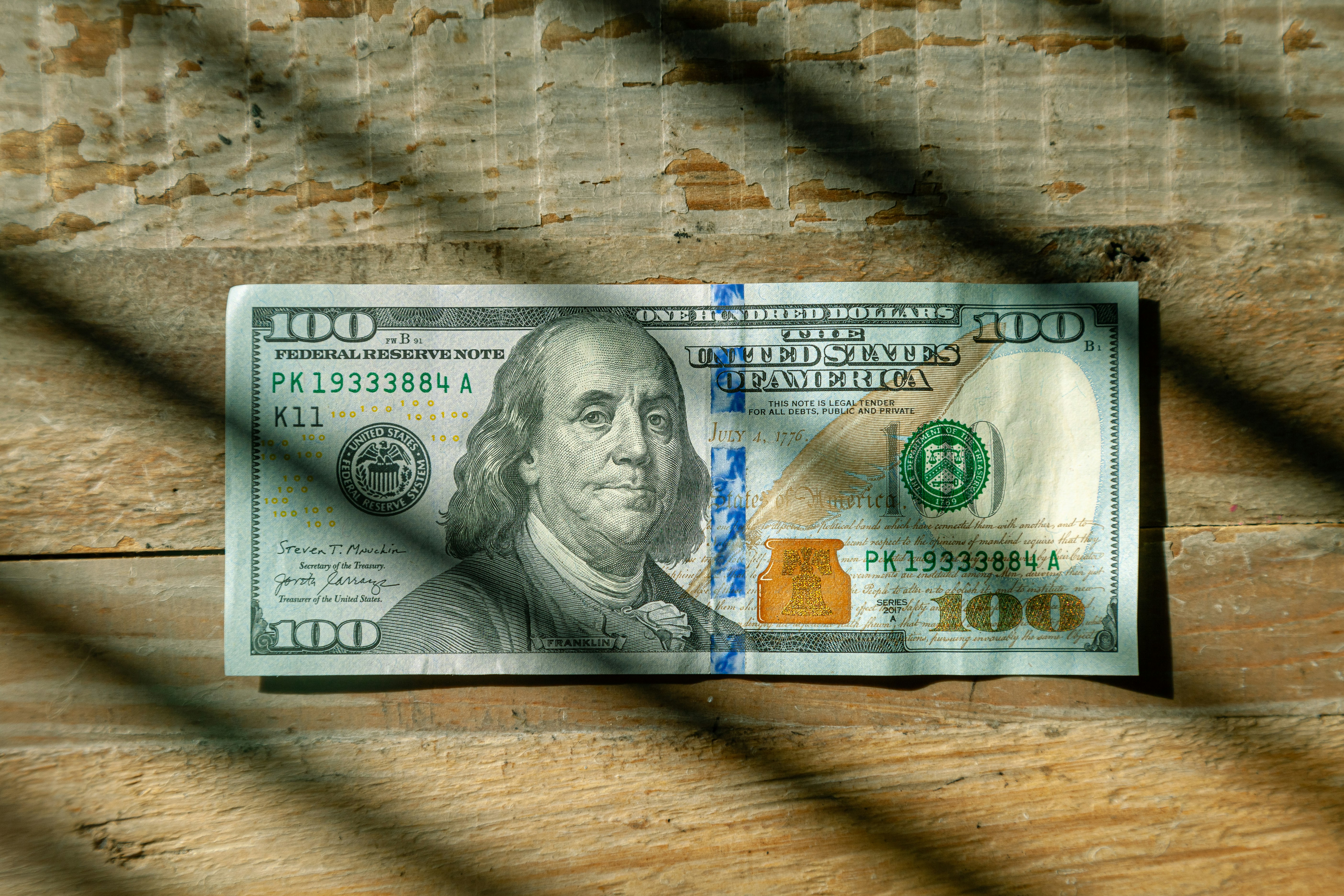 US Currency One hundred dollar bill flat lay on wood background