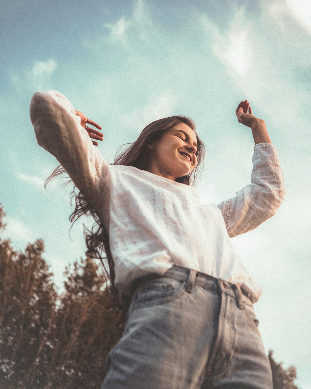 mulher na camisa branca de manga comprida e jeans jeans azuis