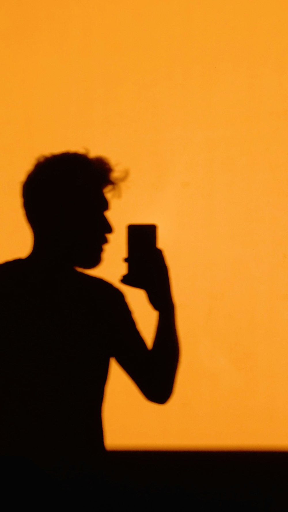 silhouette of man holding smartphone