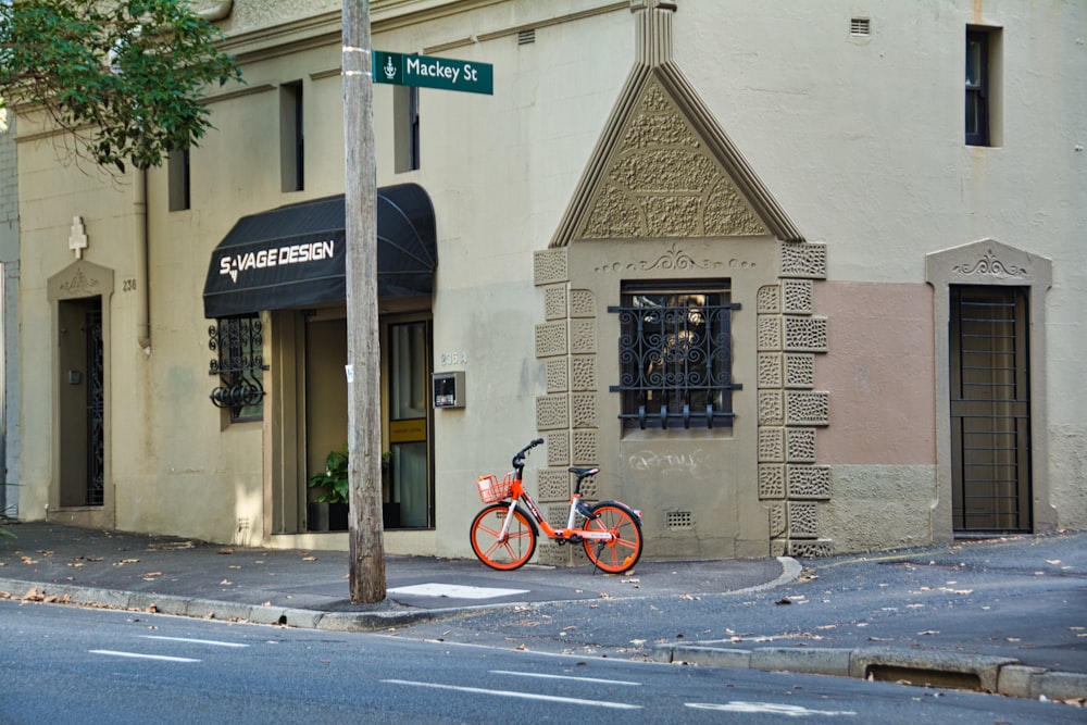 red bicycle parked beside gray concrete building during daytime