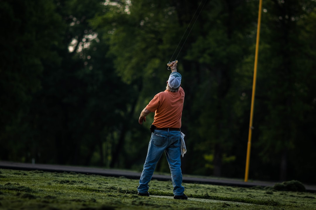 man in orange shirt and blue denim jeans playing golf during daytime