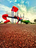 Playground scene with children climbing, sliding, and laughing under a warm sun.