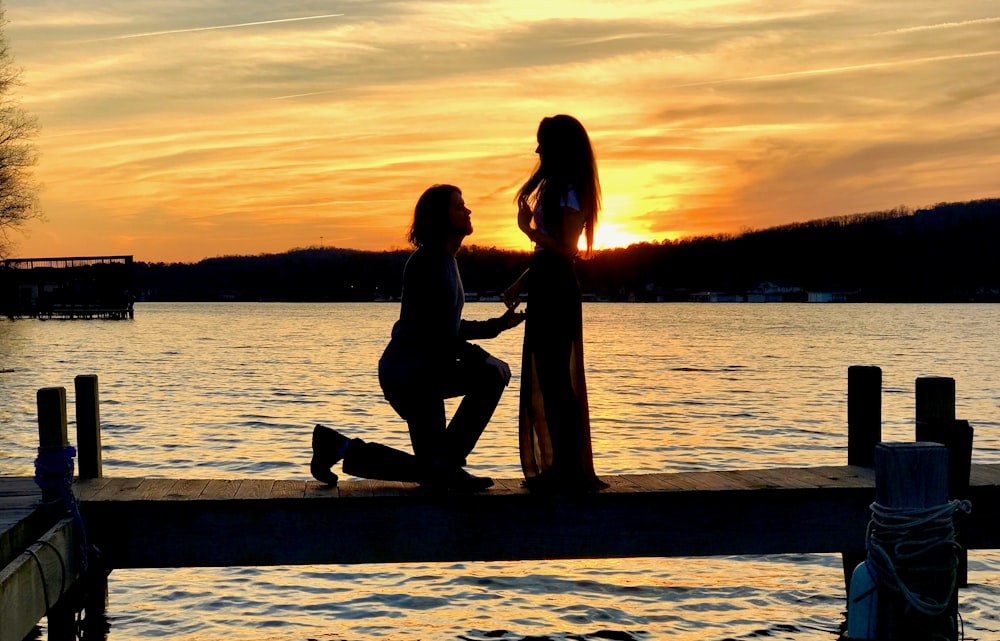 casal sentado na doca de madeira durante o pôr do sol