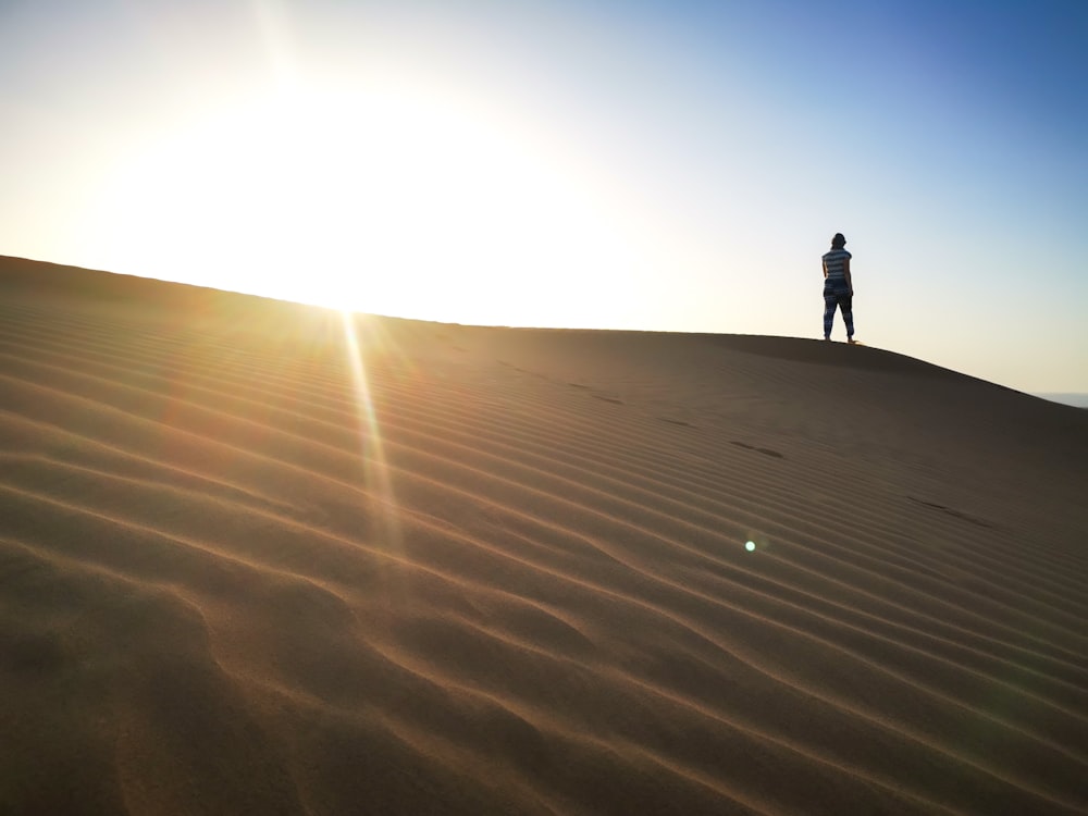 silhouette of person standing on sand during daytime