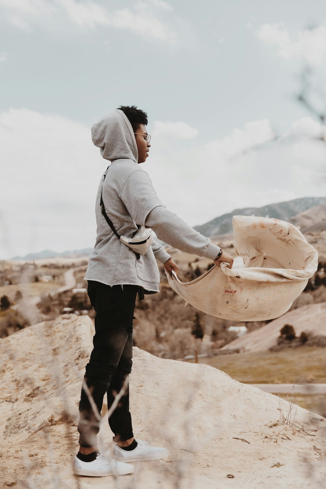 man in gray hoodie and black pants holding brown hat