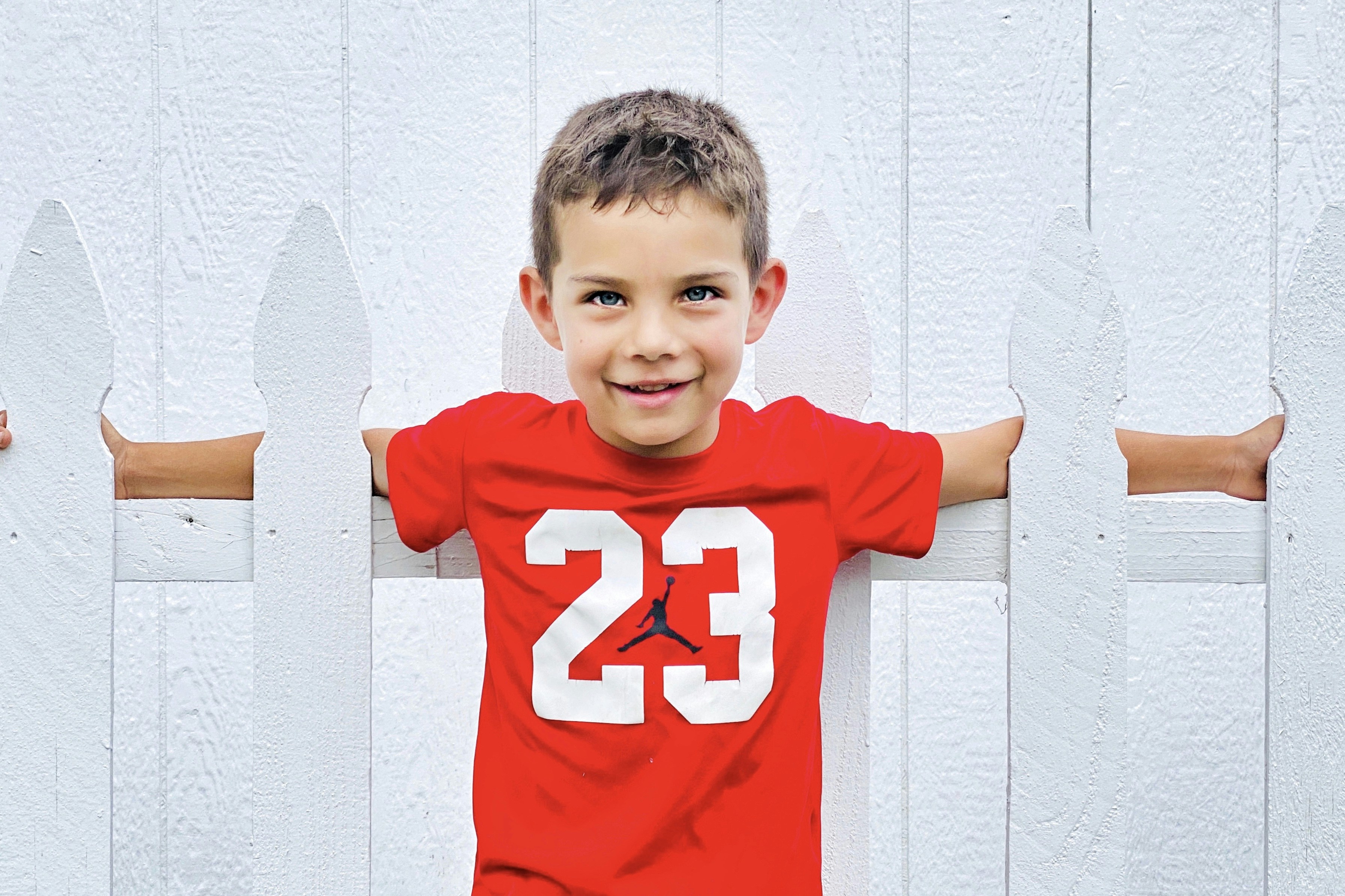 boy in red and white crew neck t-shirt leaning on white wall