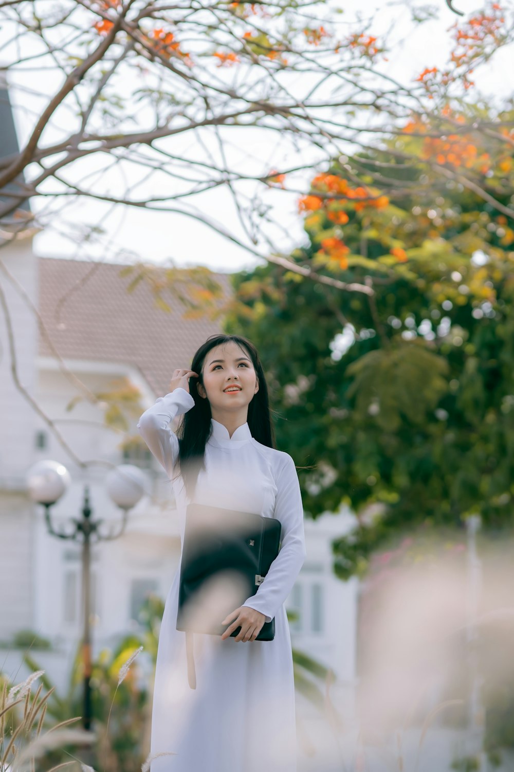 woman in white long sleeve shirt standing near tree during daytime