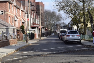 Street view of a quiet neighborhood with houses lined up and parked cars