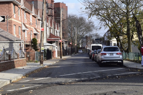 Street view of a quiet neighborhood with houses lined up and parked cars