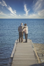man and woman kissing on wooden dock during daytime