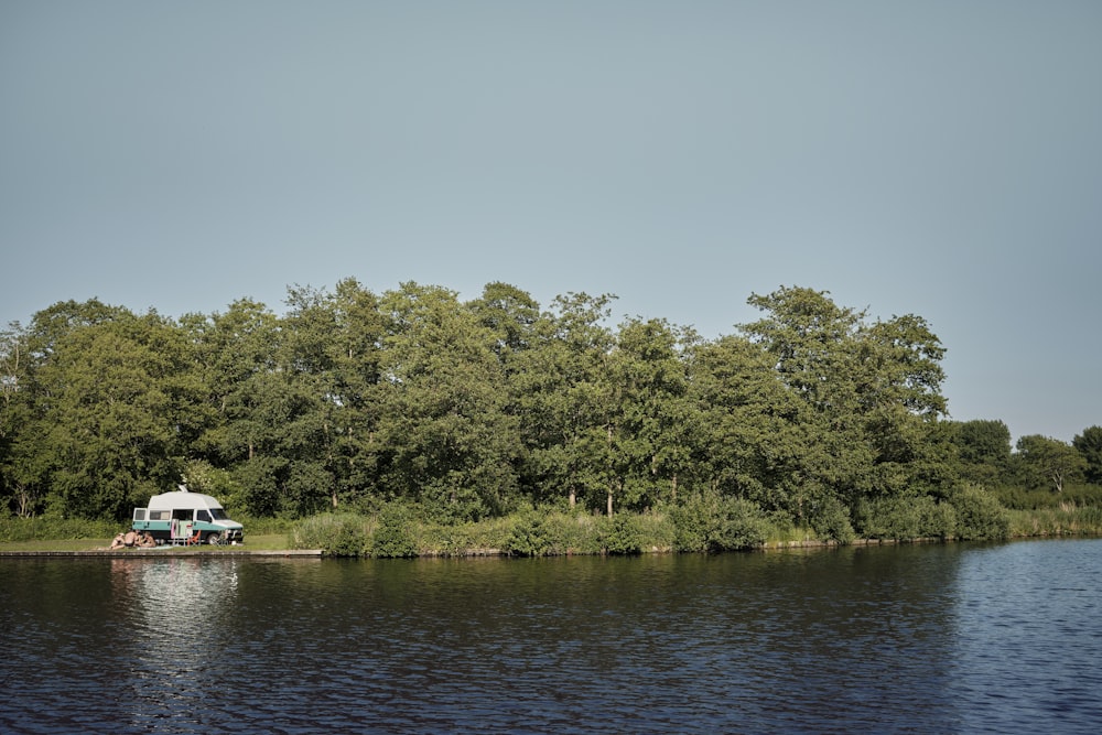 white boat on river near green trees during daytime