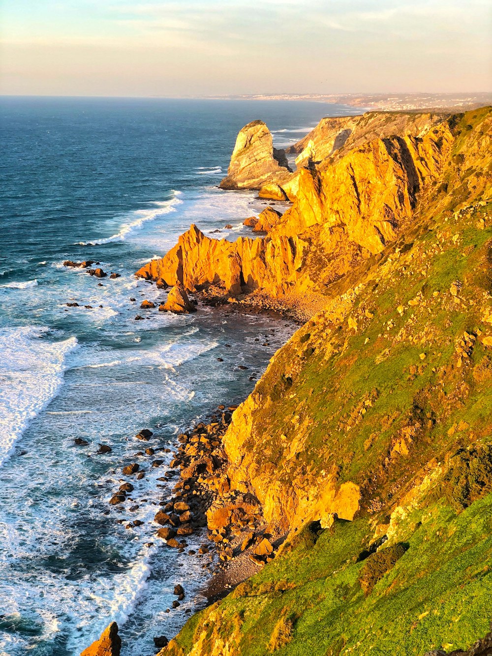 green and brown rock formation beside sea during daytime