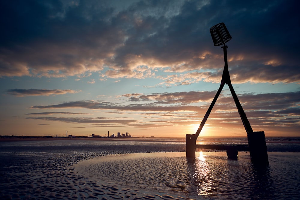 silhueta da pessoa em pé na praia durante o pôr do sol