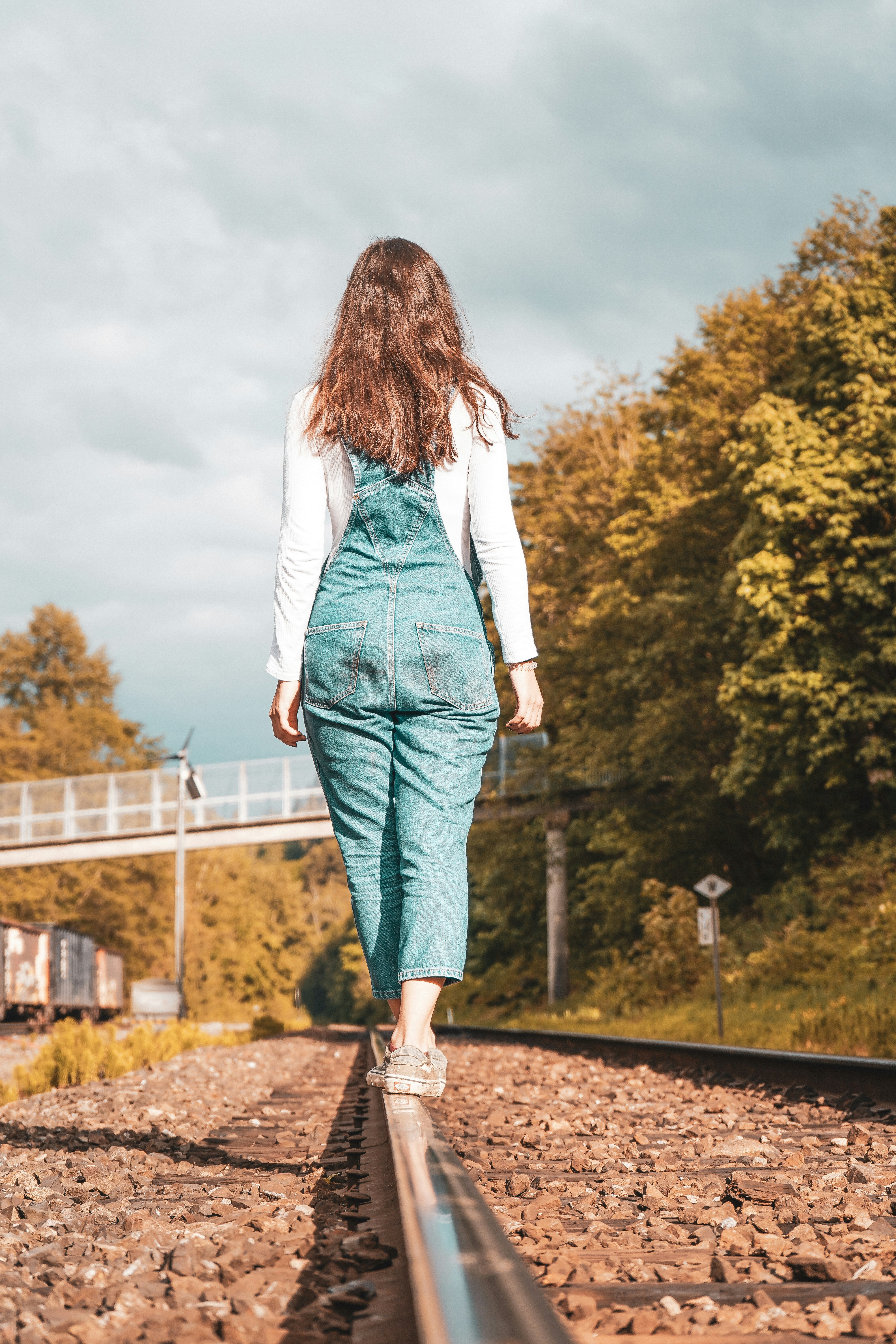 woman in white long sleeve shirt and green skirt standing on brown dried leaves during daytime