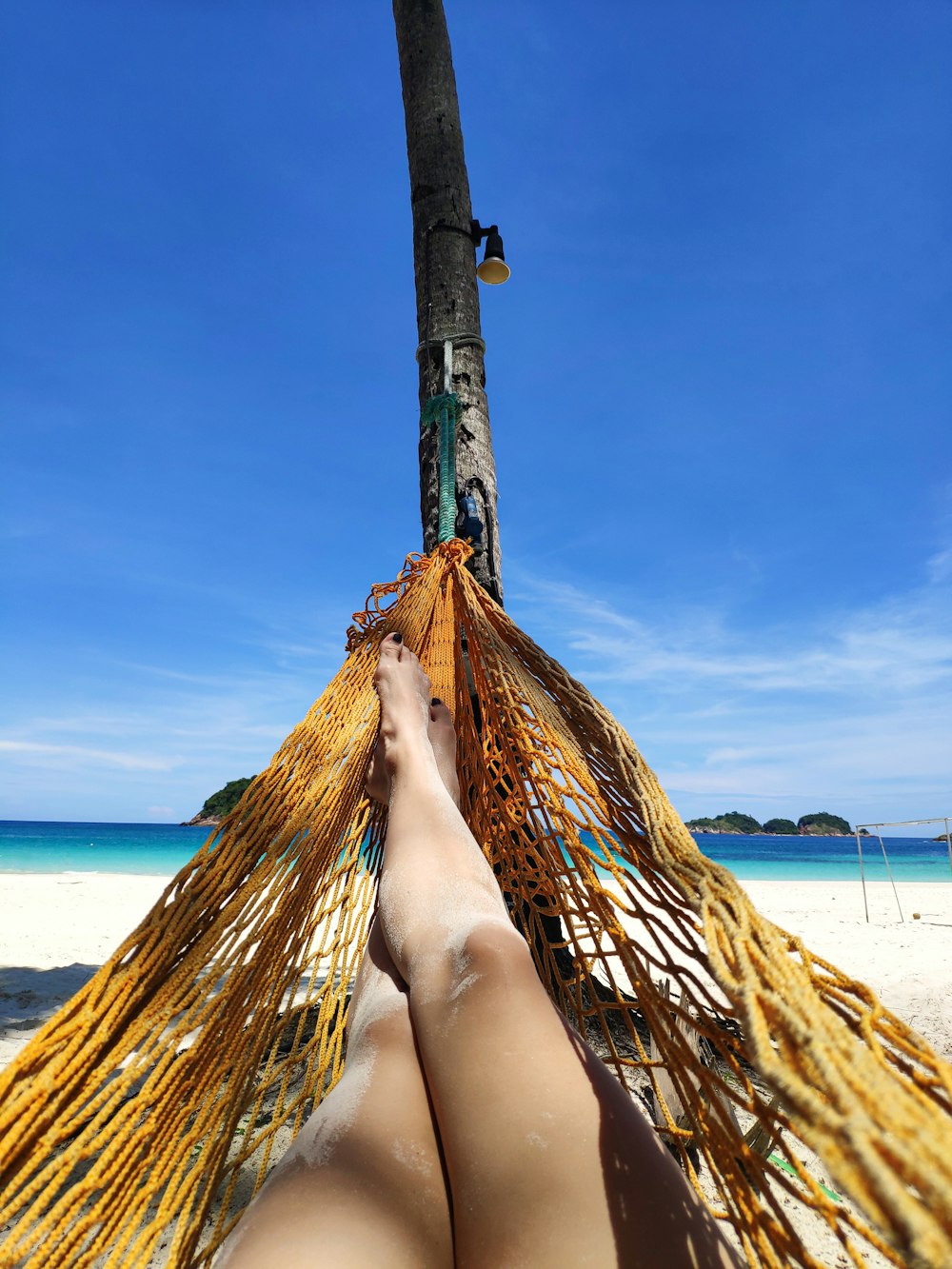 person lying on hammock near body of water during daytime