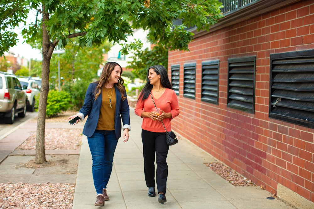 two women walking down a sidewalk talking to each other