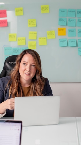 woman in black shirt sitting on chair in front of laptop computer