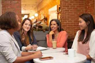 Situativ: Vier Personen sitzen in einem Café und sind in ein Gespräch vertieft.
