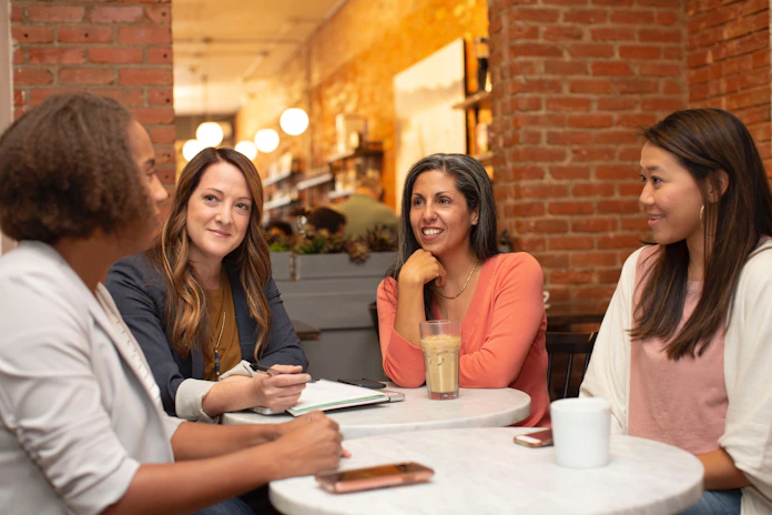 A vibrant group of women sharing laughter and ideas over coffee in a cozy living room.