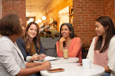 four women chatting at cafe table