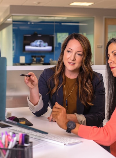 two women sitting at a table looking at a computer screen