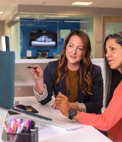 two women sitting at a table looking at a computer screen