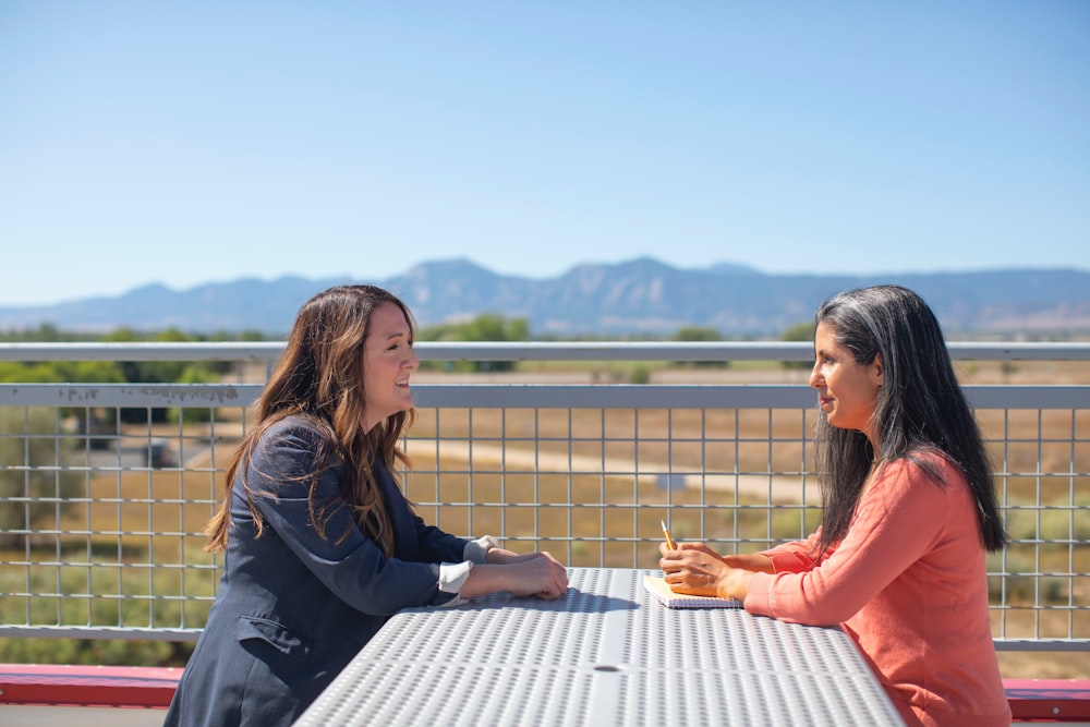 woman in black long sleeve shirt sitting on white wooden bench during daytime