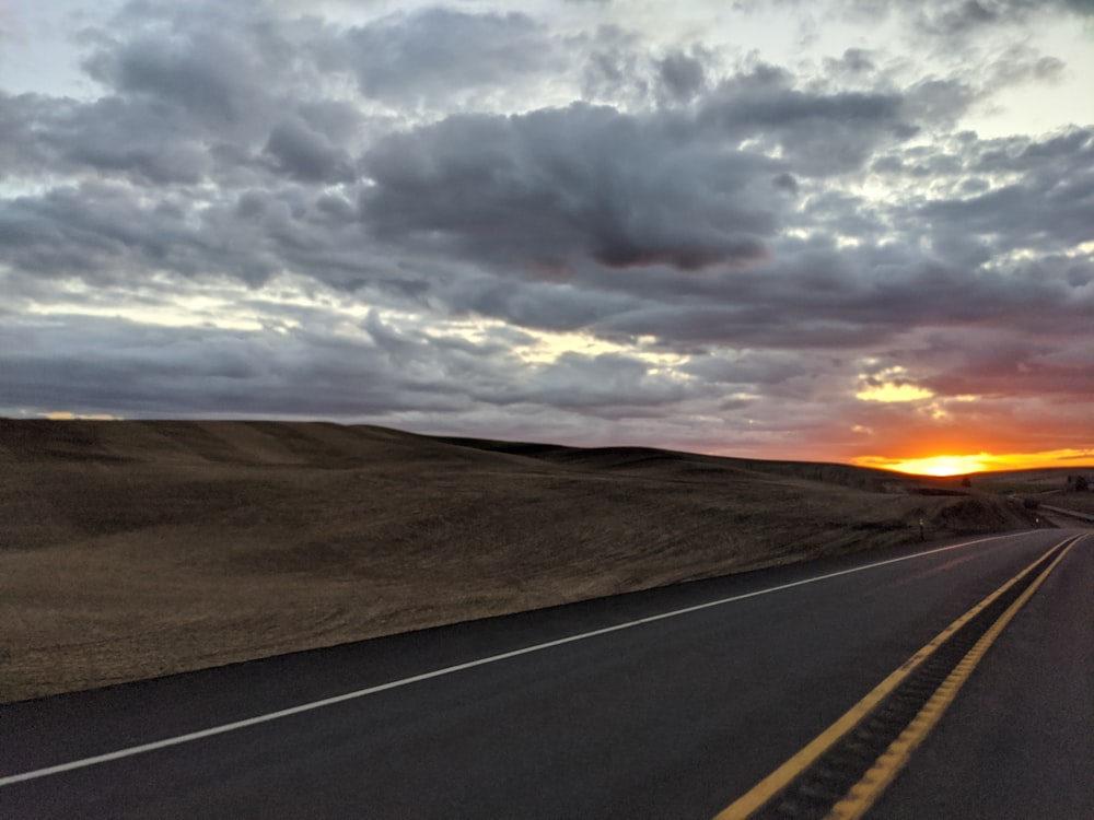 gray asphalt road under cloudy sky during daytime