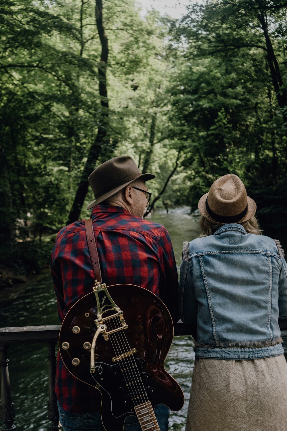 man in blue denim jacket and brown cowboy hat playing guitar